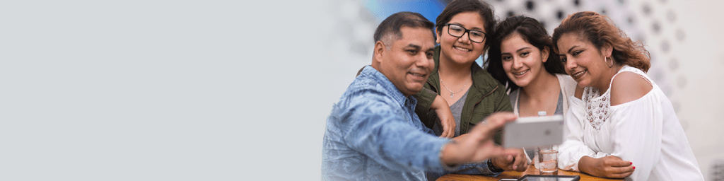 Feliz familia hispana de cuatro al aire libre con el padre tomando una selfie en su teléfono